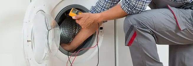 Dryer repair technician inspecting and repairing a clothes dryer in Tulsa, OK