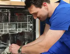 Dishwasher repair technician inspecting and servicing an open dishwasher in Tulsa, OK