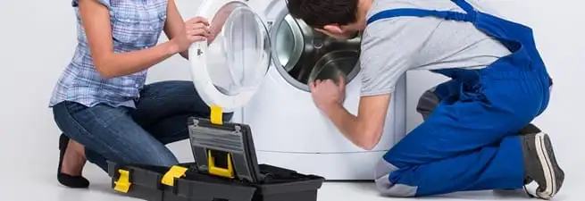 Washer repair technician inspecting a front-load washing machine with tools in Tulsa, OK