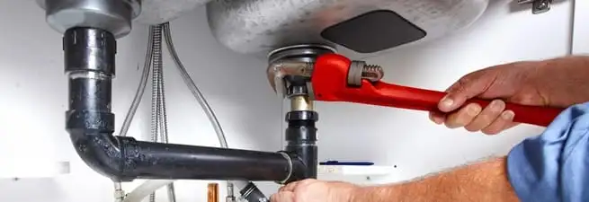 Garbage disposal repair technician tightening the sink drain and disposal connection in Tulsa, OK