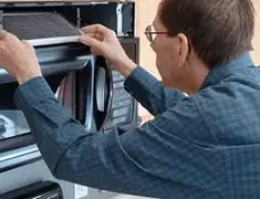 Appliance repair technician replacing a microwave vent filter in Tulsa, OK