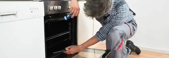 Oven repair technician inspecting and servicing an electric oven in Tulsa, OK