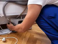 Appliance repair technician fixing refrigerator water line and connections in Tulsa, OK