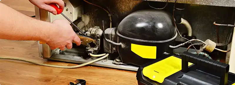 Refrigerator repair technician fixing the compressor and wiring in Tulsa, OK