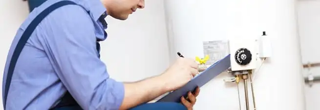 Water heater repair technician inspecting the unit and recording service notes in Tulsa, OK