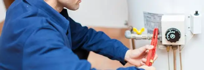 Water heater repair technician adjusting the temperature control and gas valve in Tulsa, OK